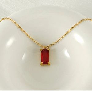 Detail of 18K gold plated necklace with rectangular red zircon pendant in ceramic bowl