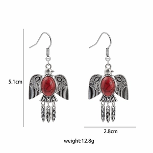 Detail view of ethnic eagle feather drop earrings with size markers and red stone inlay