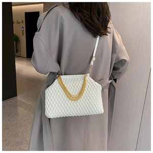 Close-up of white quilted handbag with gold chain detail on a model in a grey coat