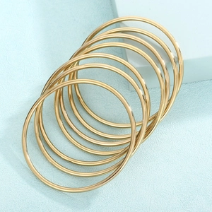 Detail of stacked 3mm golden stainless steel bangles with polished metallic finish