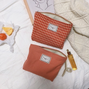 Orange houndstooth cotton makeup bag with metal zipper and minimalist label on white fabric