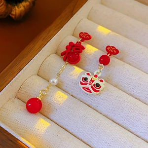 Macro view of asymmetric New Chinese lion and Fu character drop earrings on beige velvet