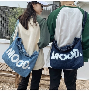Outdoor back view of blue denim tote bags with large MOOD print for casual styling