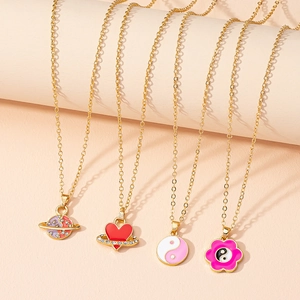 Close-up of four gold-plated necklaces featuring pink planet and yin yang heart pendants