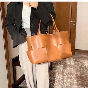 Close-up of brown woven leather texture and handles on a large fashion tote bag
