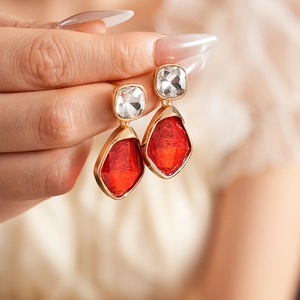 Détails de boucles d'oreilles vintage en or avec pierres claires et rouges sur modèle