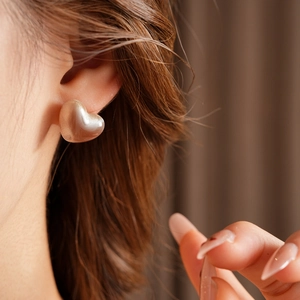 Mannequin portant des boucles d'oreilles cœur en résine beige effet nacré