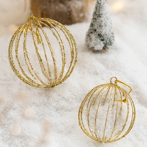 Glittering gold hollow iron Christmas ball ornaments on white snow with bokeh light background
