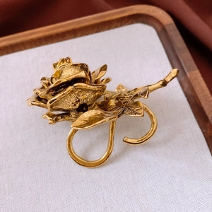 Detailed top view of a gold rose ring with vintage texture on a rustic wooden tray