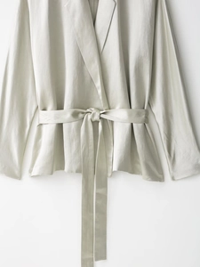Dettaglio blazer in raso grigio-verde con trama in seta e cintura in vita