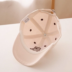 Detail of baby baseball cap interior showing 100% cotton label and bear embroidery