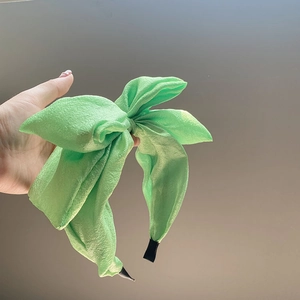 Close-up of a green seersucker oversized bow headband with textured fabric detail