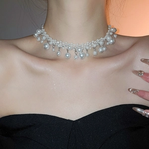 Close-up of woven pearl necklace with tassels and pendants on a female model