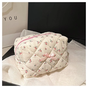 Detail of quilted floral makeup bag with pink satin bow and premium fabric texture