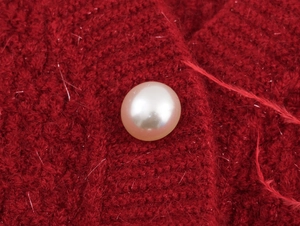 Macro della texture a maglia rossa con lunghe fibre di mohair e un bottone di perla