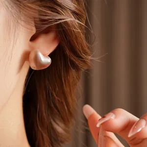 Elegant heart-shaped resin stud earrings in silk gold finish worn by a model