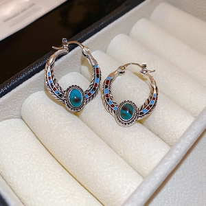 Macro view of vintage silver earrings with turquoise inlay and colorful enamel details