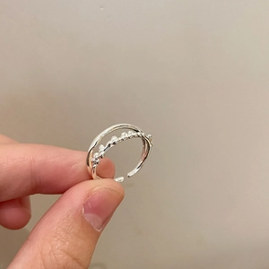 Close-up of a silver double-layered open ring with minimalist beaded texture on a finger
