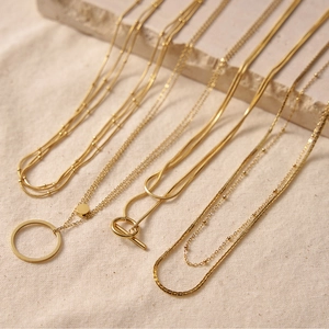 Detail of 18K gold-plated layered necklaces featuring snake chains and ring pendants