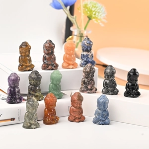 Natural crystal Buddha figurines in various gemstones placed on a book surface