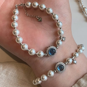 Silver bracelet with white pearls, S925 silver clasp and blue gemstone center on wrist