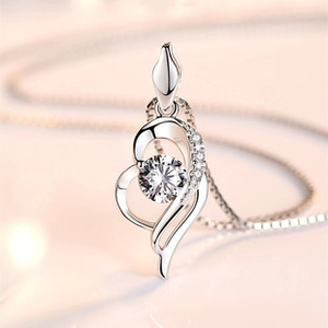 Detailed macro view of a silver heart-shaped pendant with rotating central crystal
