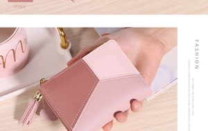 Gros plan d'un portefeuille rose pour femme avec patchwork géométrique et zip à pompon