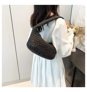 Close-up of black floral embossed shoulder bag with soft quilted texture shown on a model
