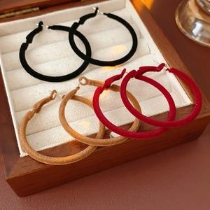 Detailed view of three pairs of flocked hoop earrings in black, brown and red colors