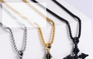 Close-up of punk vajra pestle pendants in silver, gold and black on box chains