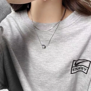 Detail of silver double layered chain necklace with square pendant on grey sweatshirt