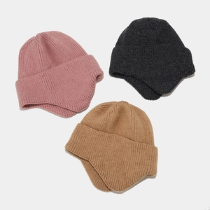 Three solid color knit trapper hats in pink, dark grey and camel with ear protection