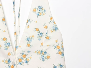 Détail macro du tissu en popeline à imprimé floral bleu et orange avec un bouton