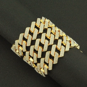 Close-up of gold iced-out Cuban chain bracelet with paved diamonds on dark background