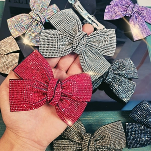 Elegant oversized rhinestone bow hair clip shown in multiple colors including red and silver
