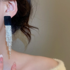 Dettaglio di orecchini quadrati in velluto nero con nappe di diamanti su una modella