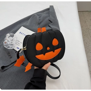 Detail of black pumpkin crossbody bag with orange face patch and bat charm detail