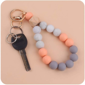 Detail of grey and peach silicone beads with geometric wooden bead and gold keychain