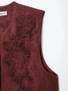 Dettaglio ravvicinato di gilet bordeaux in camoscio con ricami floreali 3D eleganti