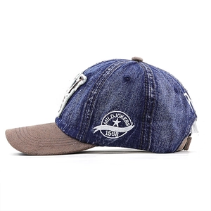 Detail view of denim baseball cap featuring white side embroidery and contrast brown brim