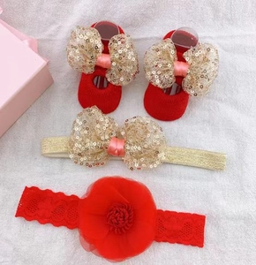 Detail of red baby headbands and socks with gold sequin bows on white texture