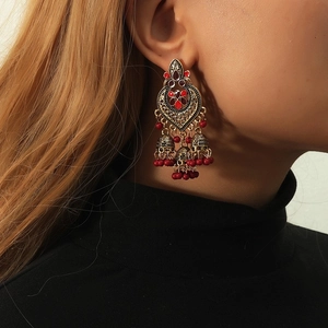Close-up of bohemian heart-shaped Jhumka earrings with red beads and vintage gold finish