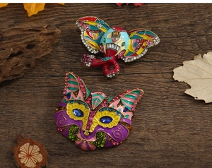 Artistic enamel brooches in elephant and cat shapes with rhinestones on wood background