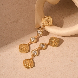 Detailed view of vintage gold lion earrings with square crystal on beige stone
