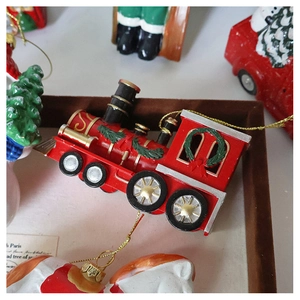 Detail of red Christmas train ornament with green wreath and golden cord on brown tray