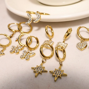Close-up of gold hoop earrings set with zircon stars, moons, hearts, and butterflies