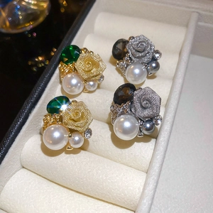Détail de boucles d'oreilles roses vintage avec pierres vertes et perles en boîte blanche