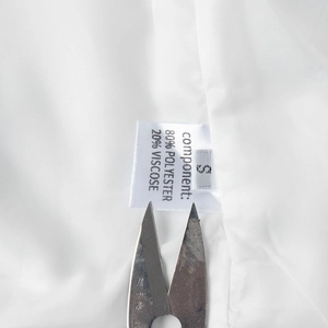 Detail of white vest lining showing the size S and polyester blend fabric care label