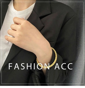 Detail of woven texture on golden titanium steel open bangle worn with casual outfit