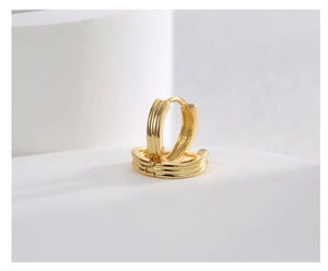 Macro detail of gold-plated hoop earrings featuring a unique triple-line wavy texture
